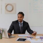 Professional businessman working at desk with laptop and documents in modern office.
