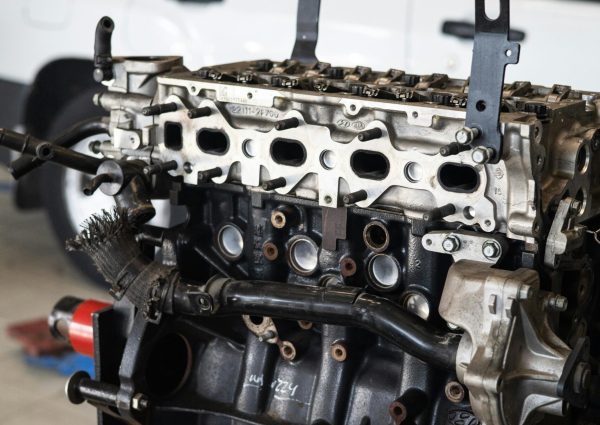 Detailed view of a car engine in an auto repair shop with a blurred vehicle in the background.